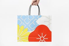 a hand holding a shopping bag with an abstract design