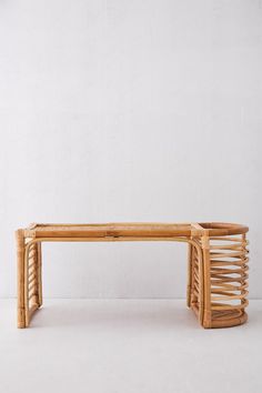 a wooden bench made out of wickers on a white floor with a wall in the background