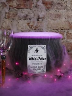 a witch's pot with purple lights around it and a wine glass next to it