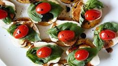 small appetizers with tomatoes and spinach are arranged on a white platter