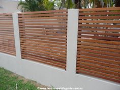 a wooden fence with vertical slats on the top and bottom, in front of a house