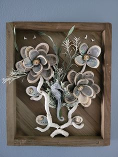 a wooden frame with shells and flowers on it