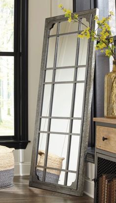 a mirror sitting on top of a wooden floor next to a vase with yellow flowers