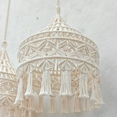 two white macrame hangings with tassels on them