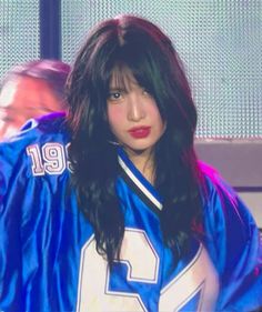 a woman with long black hair wearing a blue jersey