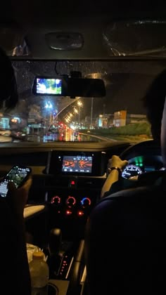 two people sitting in a car playing a game on the nintendo wii console at night