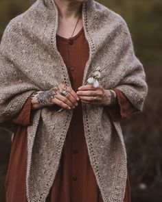 a woman with tattoos on her arm wearing a cardigan and holding a bird in her hand