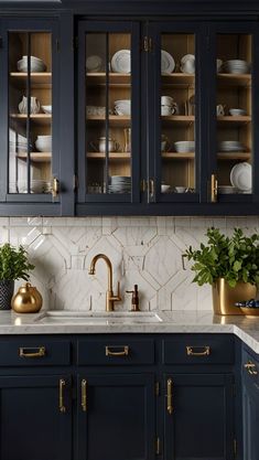 a kitchen with dark blue cabinets and white marble counter tops, gold accents on the backsplash