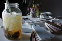 a mason jar filled with ice sitting on top of a table next to cards and papers