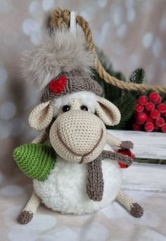 a stuffed sheep with a knitted hat and scarf on it's head sitting next to christmas decorations