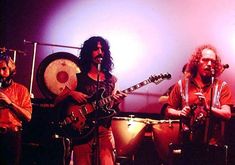 three men are playing instruments and singing on stage