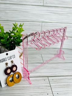 a pair of earrings is hanging on a rack next to a card and potted plant