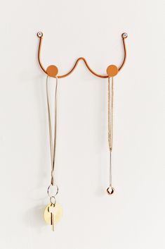 two gold and silver necklaces hanging from hooks on a white wall next to each other