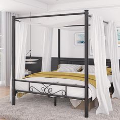 a four poster bed with white drapes on the top and yellow blankets over it