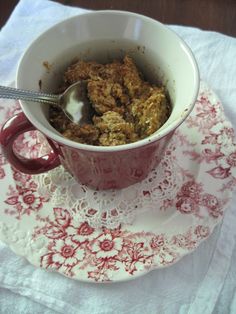 a red and white plate topped with a cup filled with oatmeal next to a spoon