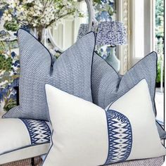 two blue and white pillows sitting on top of a couch in front of a mirror