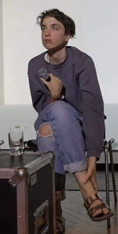 a woman sitting on top of a wooden floor next to a suitcase