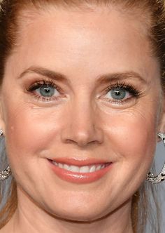 a close up of a woman with blue eyes and blonde hair wearing large diamond earrings