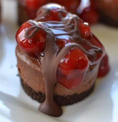 a piece of chocolate cheesecake with cherry toppings on the top and drizzled in chocolate