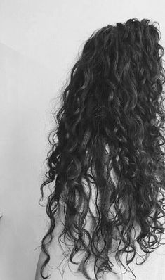 the back of a woman's head with long curly hair in black and white