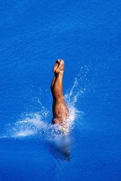 a man swimming in the blue water with his hand up to his face and head