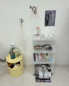 a white shelf with books and pictures on it next to a small table filled with magazines