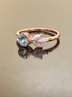 a gold ring with an opal and diamond in the center on a reflective surface