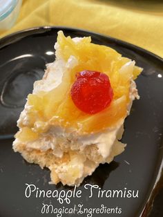 a black plate topped with a piece of cake covered in fruit