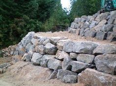 a large pile of rocks sitting on top of a dirt road next to some trees