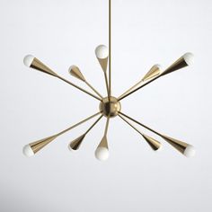 a gold chandelier with six white balls hanging from the center and five brass arms