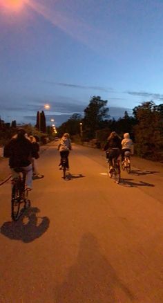 several people riding bikes down the street at night with one person on bike behind them