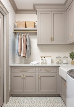 a laundry room with gray cabinets and white tile flooring, including a washer and dryer