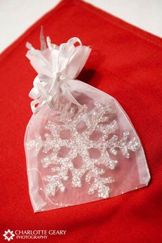 a red bag with white lace on it sitting on top of a table next to a piece of cloth