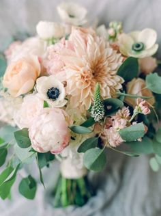 a bridal bouquet with pink and white flowers on a gray clothed tablecloth