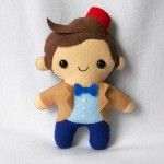 a small stuffed animal with a bow tie on it's head, wearing blue pants and a red hat