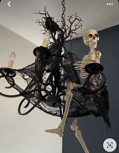 a skeleton sitting on top of a chandelier