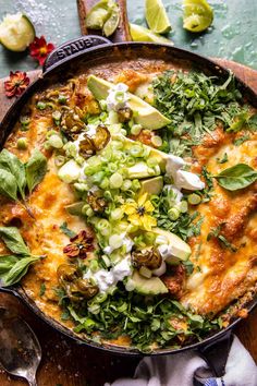 a large skillet filled with food on top of a wooden table next to utensils