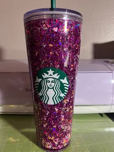 a starbucks cup with purple glitter and a green straw