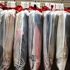 several different colored umbrellas are hanging on a rack with red ribbon around the ends