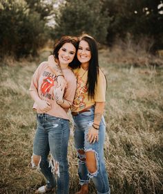 two young women standing next to each other in a field