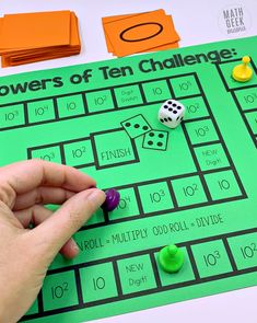 a hand is pointing at a game board with dices on it and the words powers of ten challenge