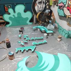 the man is working on some art work in his studio with blue and green paint