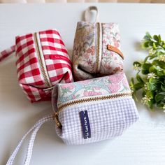 three small purses sitting next to each other on a white table with flowers in the background