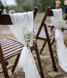 two wooden chairs with white sashes and baby's breath flowers tied to them