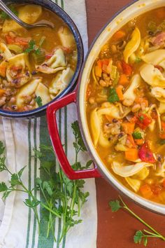 two bowls filled with pasta and meat soup on top of a table next to a spoon