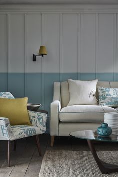 a living room with two chairs and a table in front of the couch is blue and white