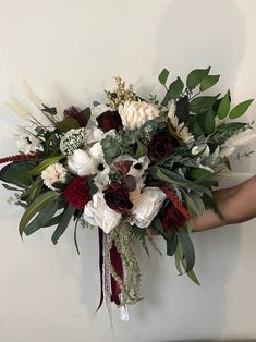 a bouquet of flowers is held up against a wall