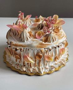 a cake with white frosting and pink flowers on it's top sitting on a table