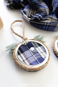 two ornaments are hanging from twine rope on a white table top with blue plaid scarves