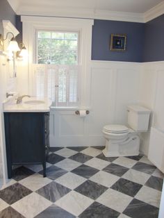 a white toilet sitting next to a sink in a bathroom under a window on top of a checkered floor